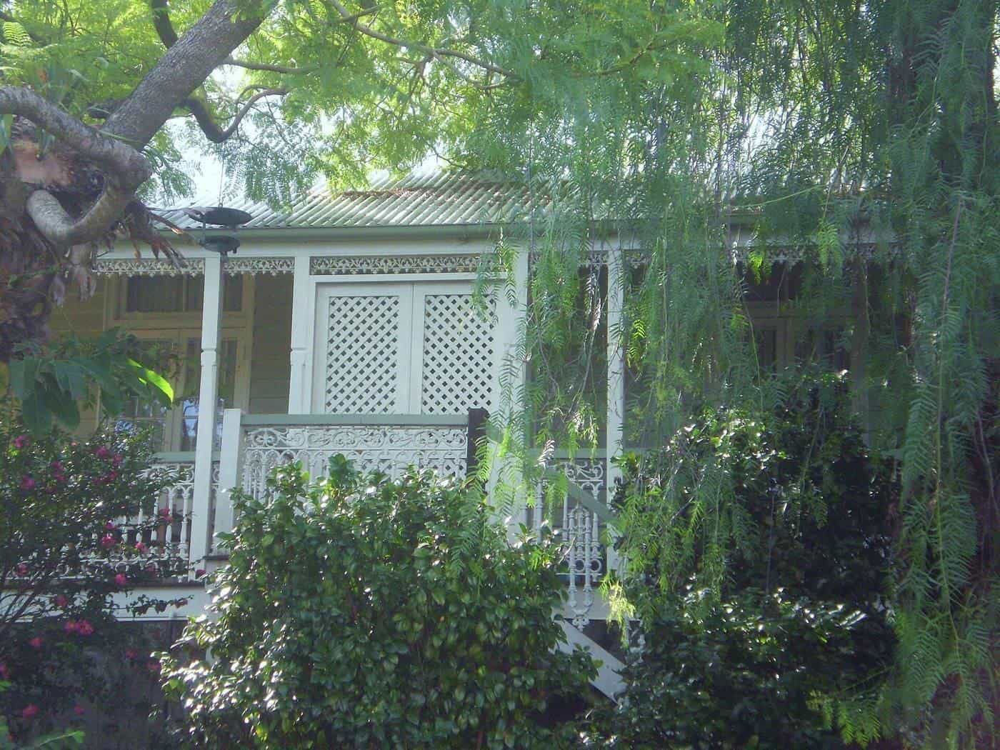 A timber verandah on a traditional house surrounded by greenery