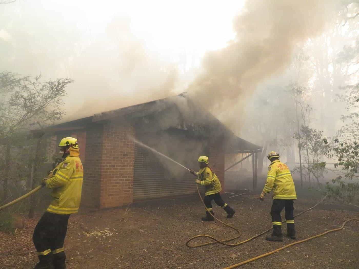 Firefighters spraying water on a burning house