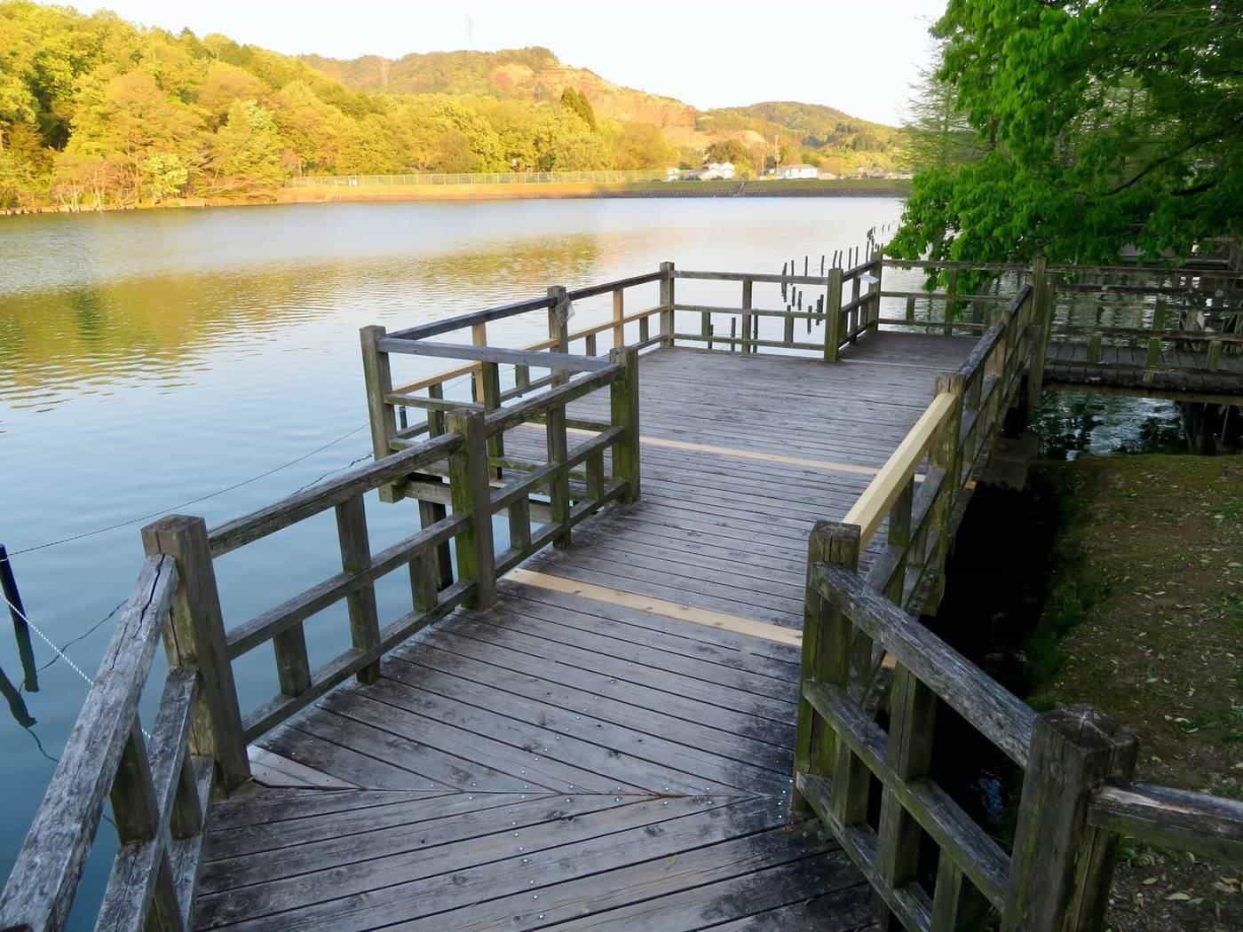 A timber boardwalk with railings beside a lake