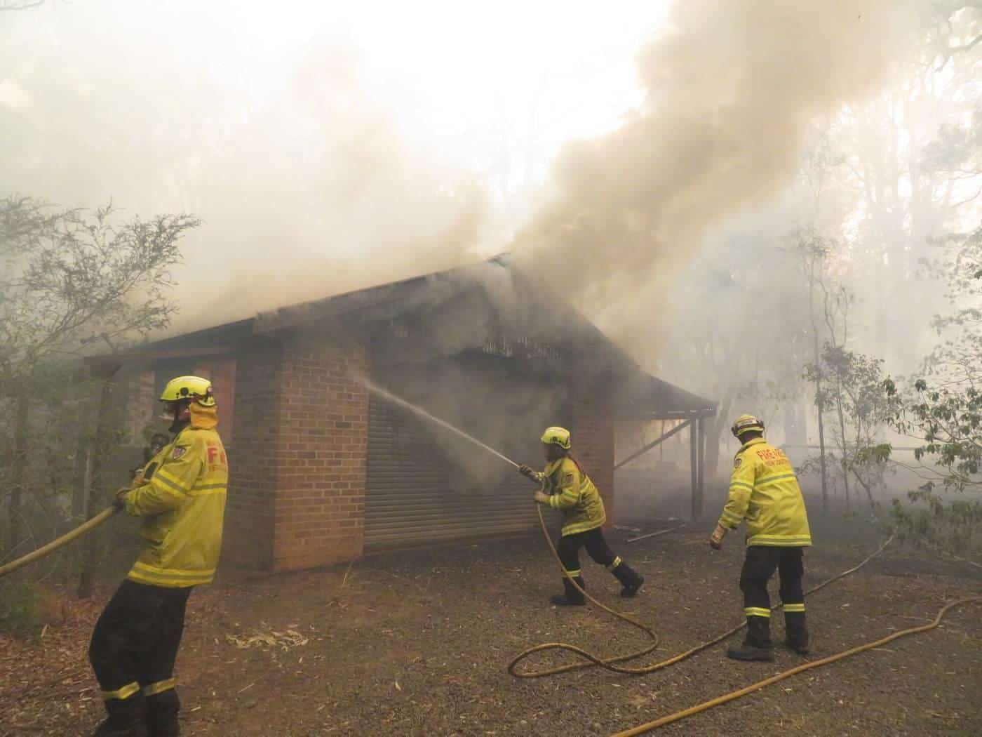 Firefighters spraying water on a burning house
