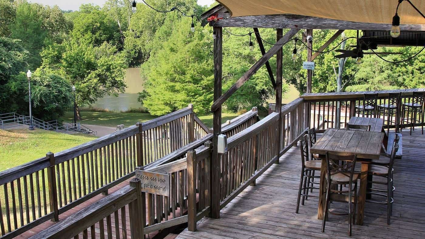 A large timber deck with an outdoor dining table and railings