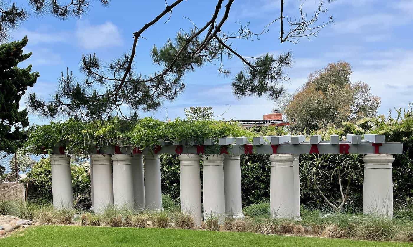 A white pergola with columns in a garden
